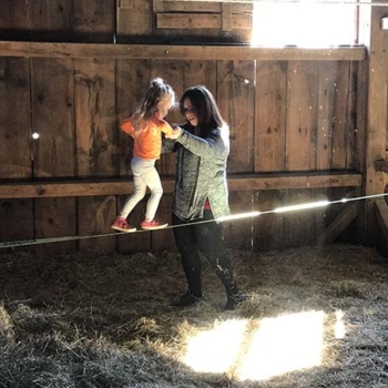 Woman supporting little girl as she walks across tightrope