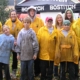 Kids and adults lined up together for group photo, with most wearing raincoats