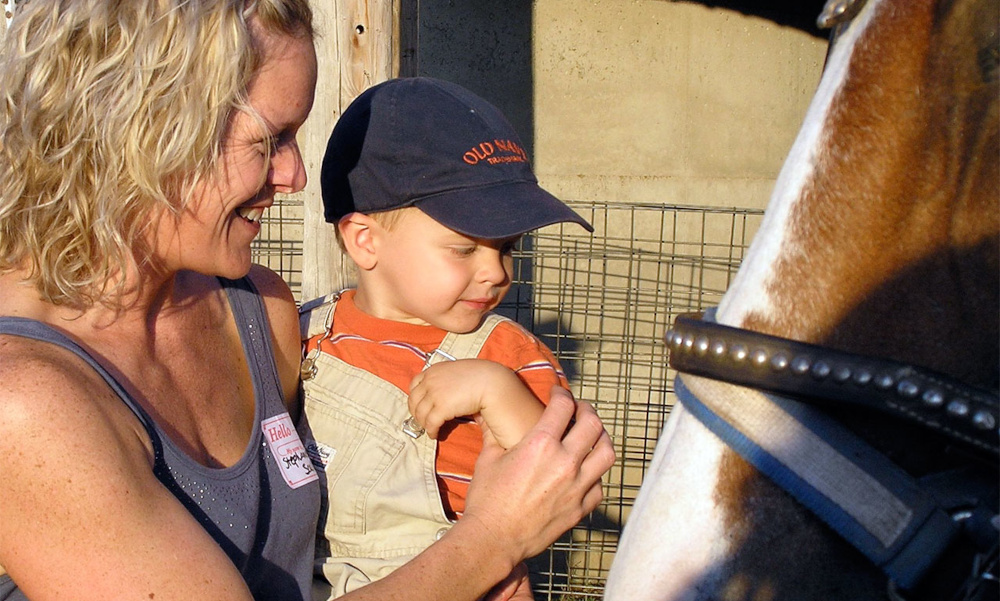 Mother and child standing next to large horse Mother and child standing next to large horse