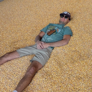 Man laying in a giant corn pit at Treinen Farm Corn Maze